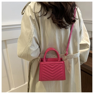Detail of rose pink quilted PU leather crossbody bag worn with a beige trench coat