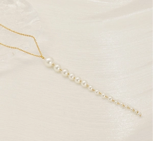 Gros plan détaillé d'un collier français en acier doré avec des perles blanches en cascade