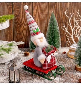Detail of grey Santa gnome with striped hat on a red and green metal sleigh
