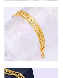 Close-up of golden dual-layered bracelet with curb and flat snake chains and lobster clasp