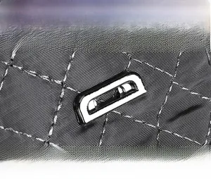 Macro view of diamond quilted fabric with a polished silver rectangular metal logo plate