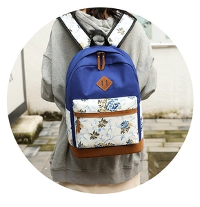 Detail of floral printed canvas backpack with brown suede bottom worn by a model outdoors
