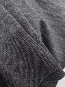 Close-up of high-quality dark grey ribbed knit fabric and detailed sweater texture