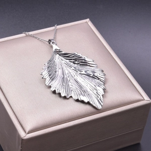 Macro shot of stainless steel leaf pendant showing realistic texture and vein details