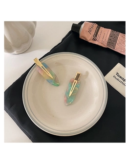 Detailed macro of colorful marbled acetate hair clips with golden metal duckbill clamps