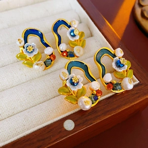 Detail of vintage flower earrings with blue enamel and pearls in a velvet jewelry box