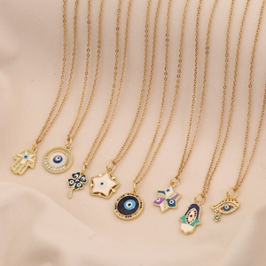Macro display of multiple gold evil eye and hamsa hand pendants on soft beige fabric