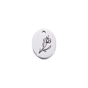 Macro detail of oval stainless steel necklace pendant with engraved black floral pattern