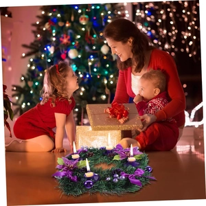 Christmas advent wreath with purple ribbons, bows and four lit candles in warm festive setting