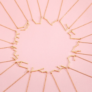 Detailed top view of twelve gold constellation necklaces arranged in a creative circle