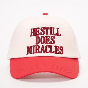 Two-tone baseball cap in off-white and red with 'HE STILL DOES MIRACLES' embroidery