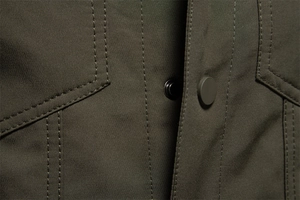 Dettaglio della giacca verde militare in lana d'agnello con tessuto twill e bottoni a pressione
