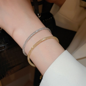 Détail de bracelets en maille or et argent minimalistes portés au poignet d'une femme