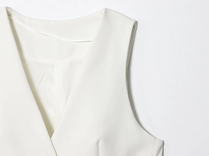 Détail du haut blanc sans manches avec col en V montrant les coutures et la texture du tissu