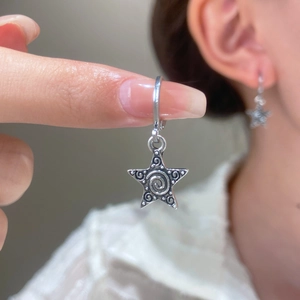 Macro detail of silver star drop earrings featuring vintage relief texture and dots