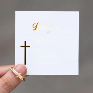 Detailed view of a gold cross ring with white zircons held next to a sentimental gift card
