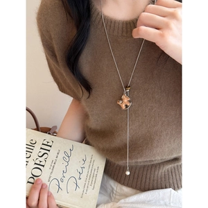 Close-up of a silver horse pendant necklace with pearl and wood bead details on a model
