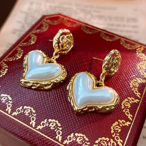 Macro view of vintage baroque heart earrings with pearl finish and gold filigree detail