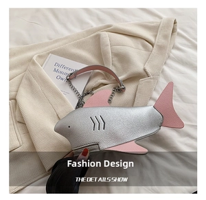 Detailed macro view of silver shark-shaped bag with pink fins and litchi grain leather texture