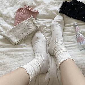 Detailed view of polka dot knit socks with lettuce trim and ribbed texture in white and pink
