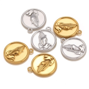 Macro detail of round gold and silver prayer hands pendants for DIY necklaces