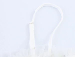 Dettaglio della spallina regolabile e del tessuto a rete sull'abito bianco elegante