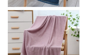 Close-up of thick absorbent cotton bath towel in mauve hanging on a wooden chair