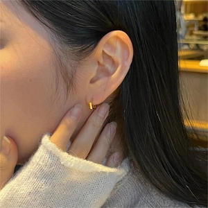 Close-up of minimalist gold hexagonal hoop earring worn on model's ear for styling
