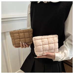 Detailed view of quilted puffer clutch bags in camel and pink colors with metal zippers