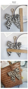 Detailed dimensions of leopard bow keychain and its aesthetic look on a handbag