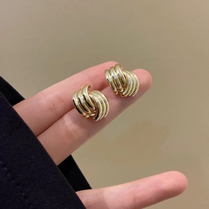 Minimalist geometric gold-plated earrings with textured stripes on a hand model