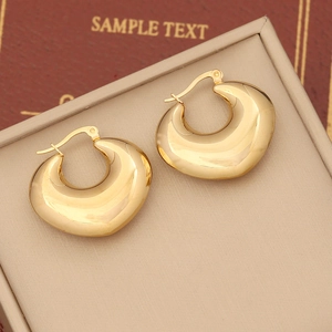 Macro shot of chunky gold hoop earrings with a high-polished mirror finish and pin closure
