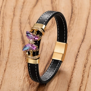 Bracelet papillon en cuir noir avec cristaux violets sur un fond de bois naturel