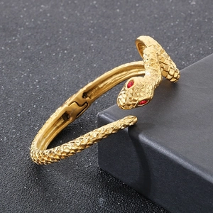 Macro shot of gold snake bracelet with red gemstone eyes on black jewelry box