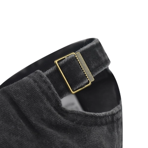 Macro view of adjustable brass buckle on washed black cotton baseball cap detail