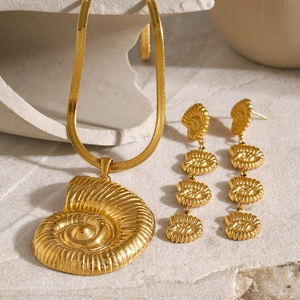 Macro shot of 18k gold conch shell jewelry set with flat snake chain and drop earrings