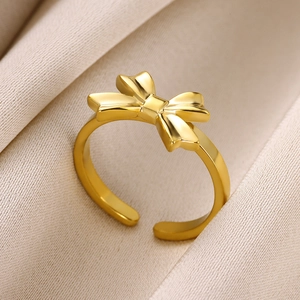 Close-up of golden bow ring with adjustable opening on beige pleated silk fabric