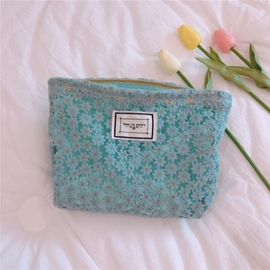 Detail of light blue floral lace clutch with a central white label on fabric background