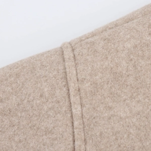 Close-up of beige wool bomber jacket showing detailed stitching and soft fabric texture