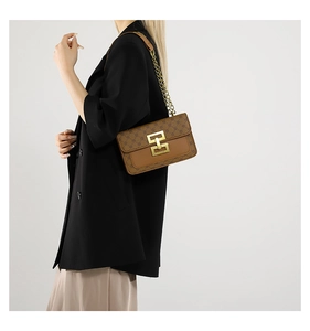 Détail d'un sac à bandoulière vintage marron avec boucle en H dorée et motif monogramme