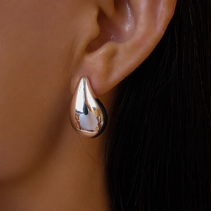Macro view of polished silver liquid drop earrings on model for a minimalist style
