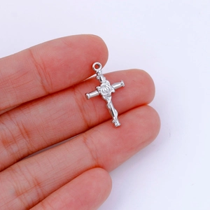 Macro detail of a silver stainless steel cross pendant featuring an intricate rose carving