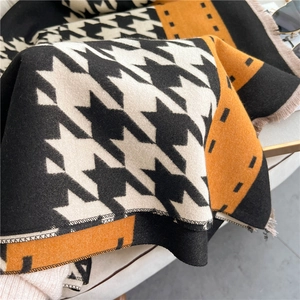 Detail of knit houndstooth pattern and orange geometric design with fringe tassels