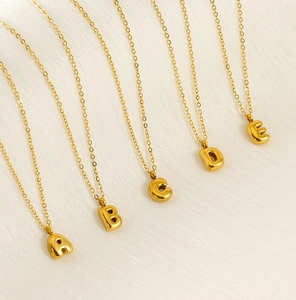 Detailed view of 18K gold bubble letter pendants A to E on a delicate cable chain