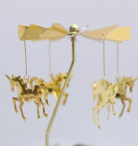 Golden rotating carousel candle holder featuring unicorn pendants on a fan blade structure