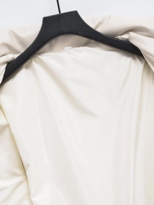 Detailed close-up of the standing collar and smooth inner lining of the beige faux leather jacket