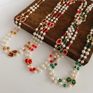 Detail of vintage multi-layer pearl necklaces with colorful crystal pendants on wood