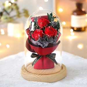 Preserved red roses and baby's breath in a glass dome with a wooden base for gift
