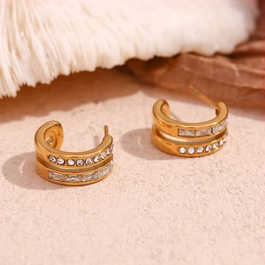 Macro detail of double-layered C-shaped gold earrings with sparkling zircon stones