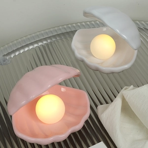Close-up of pink and white shell night lights with glowing pearls on a ripple tray